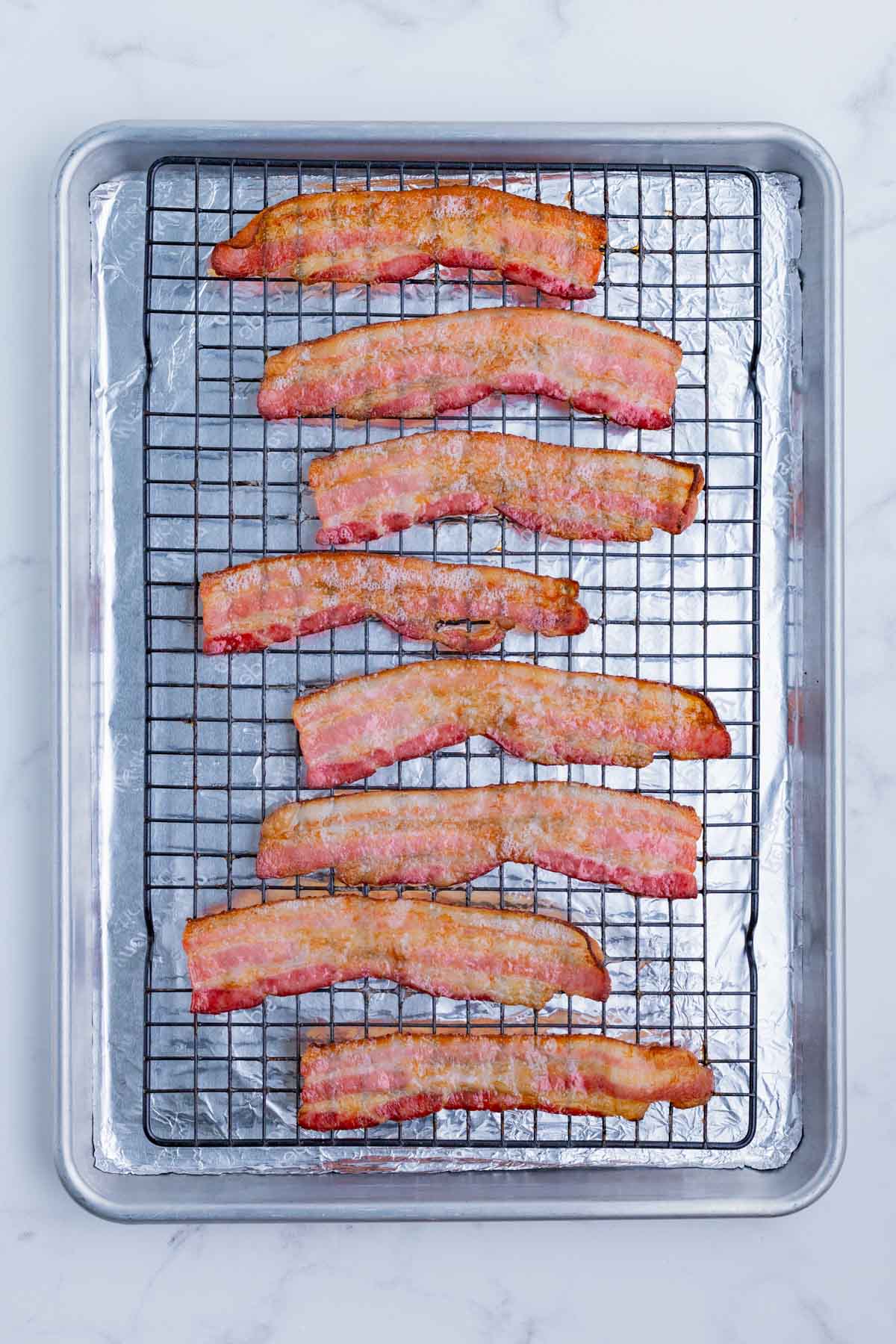 Bacon is cooked on a baking sheet with a wire rack to turn out crispy.