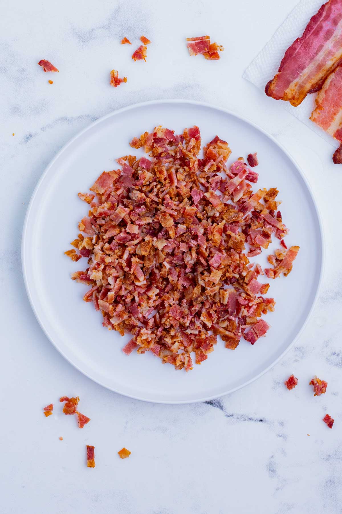 A plate full of chopped bacon pieces is ready to use.