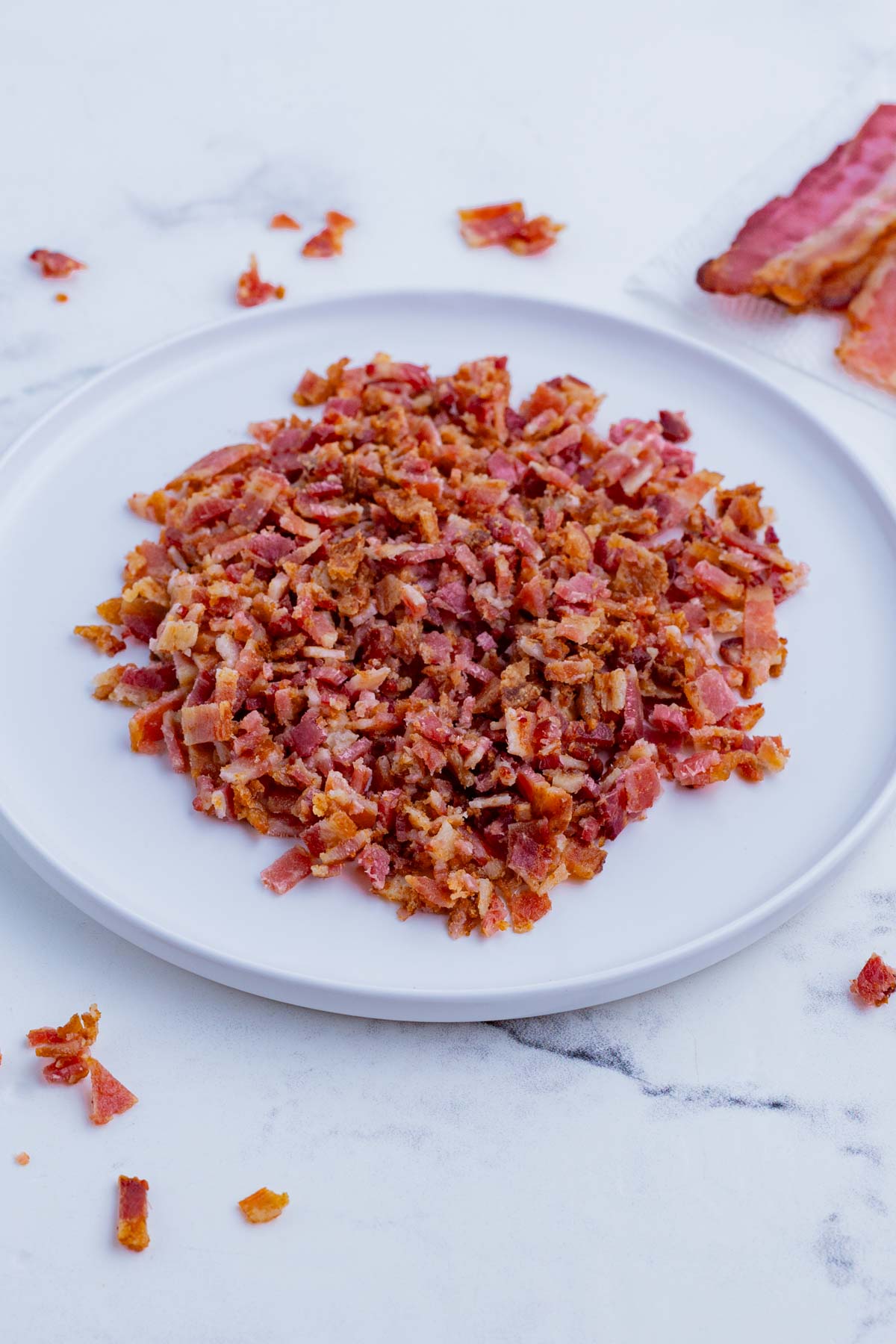 A plate full of chopped bacon pieces are ready to use.