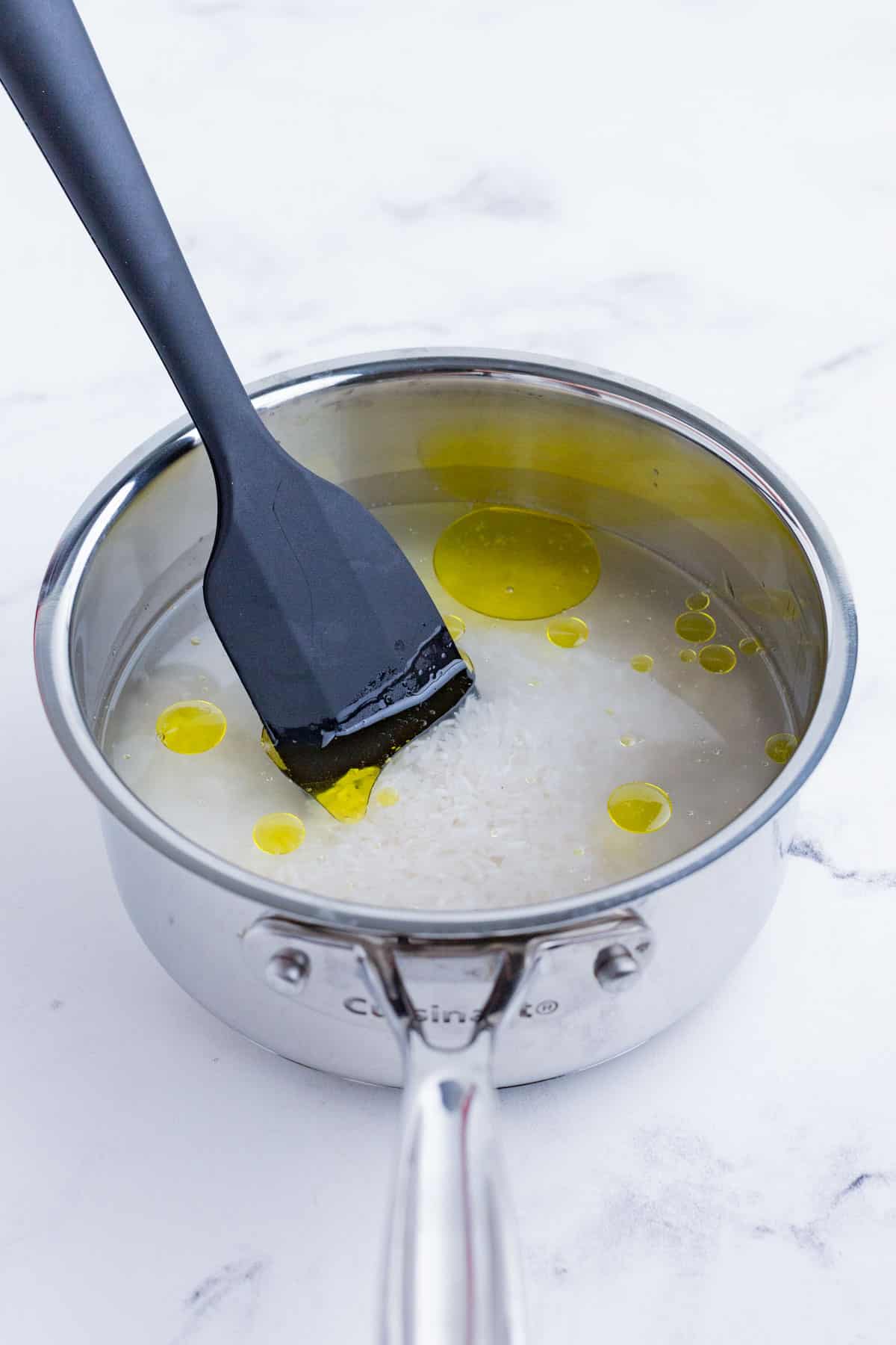 Rice, water, oil, and salt are added to a pot to cook.