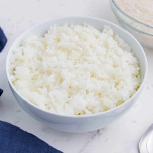 Cooked rice is served in a white bowl as an easy side dish.