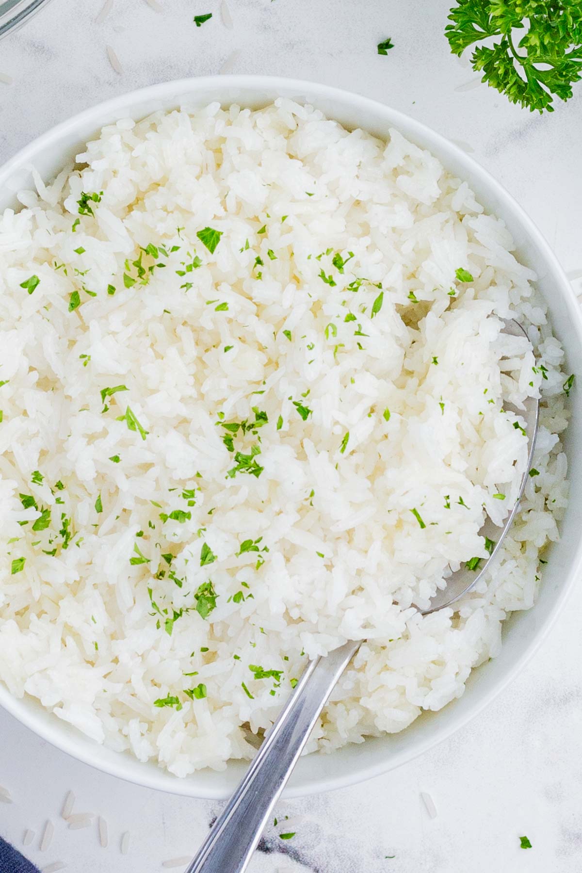 An overhead view of cooked rice seasoned with fresh herbs.