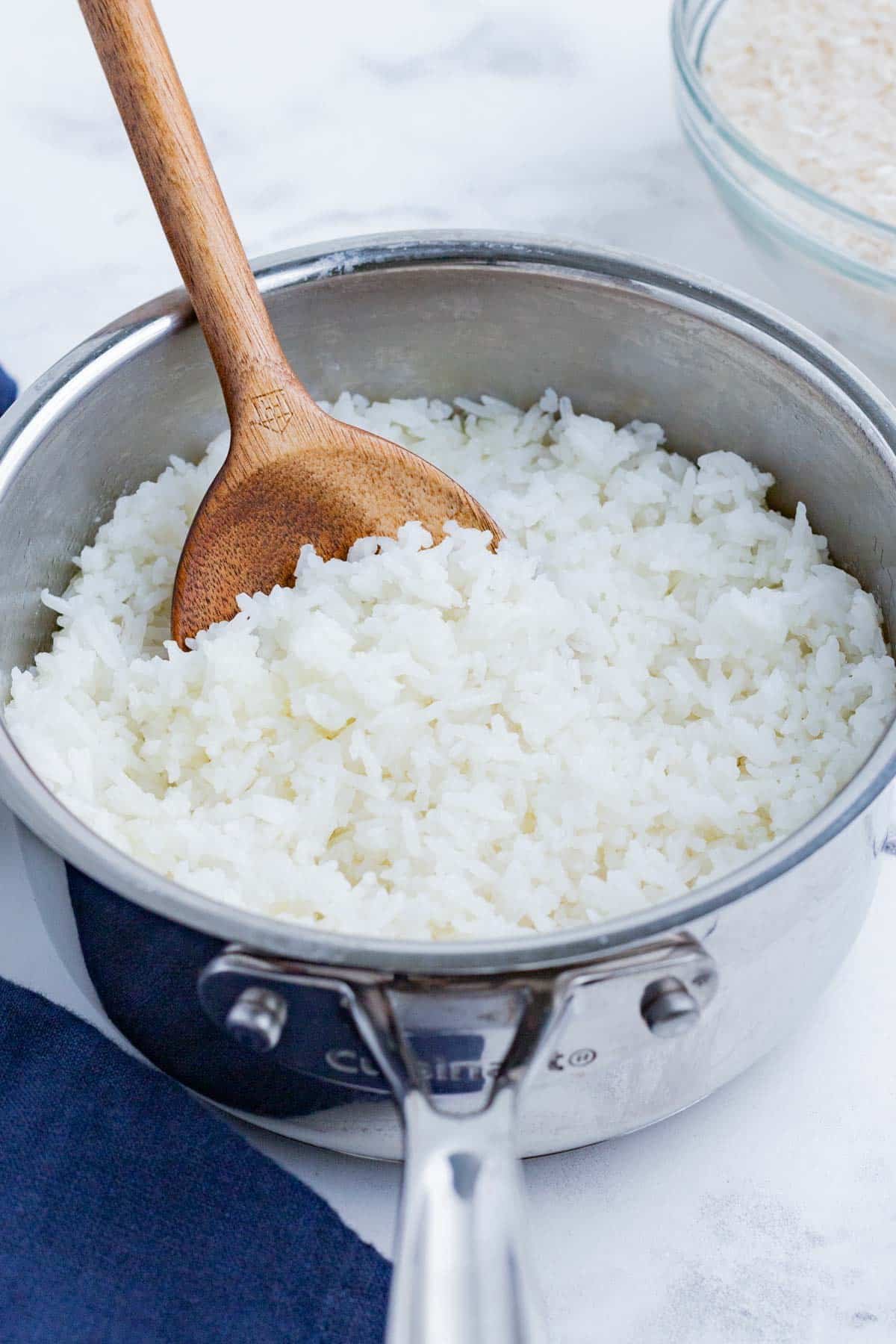 White rice cooked inside a silver pot with a wooden spoon.