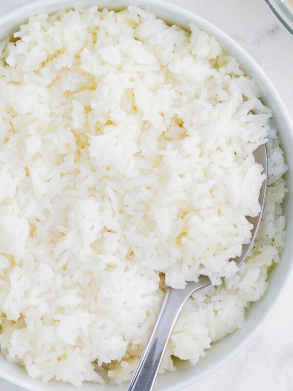 A spoon scoops cooked rice from a bowl.