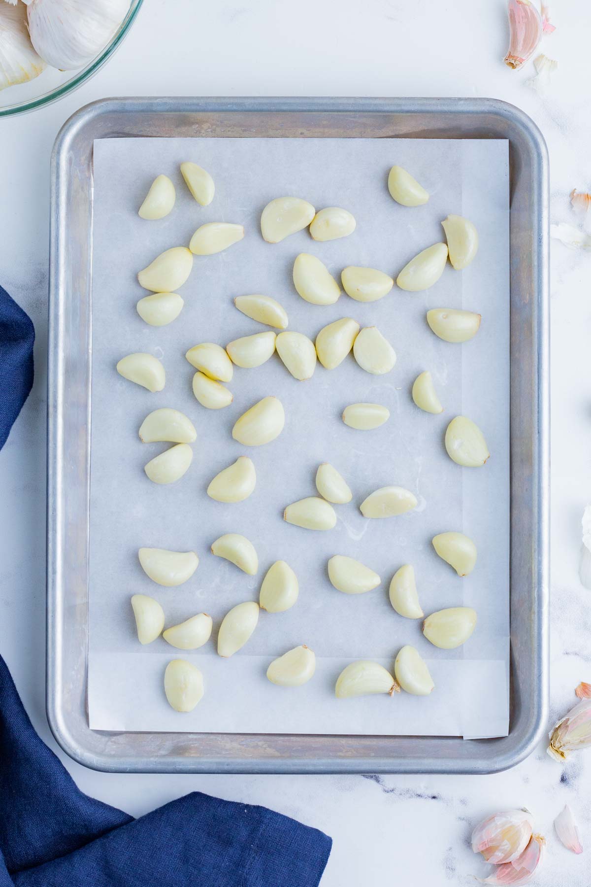Peeled garlic cloves on a cookie sheet with parchment paper.
