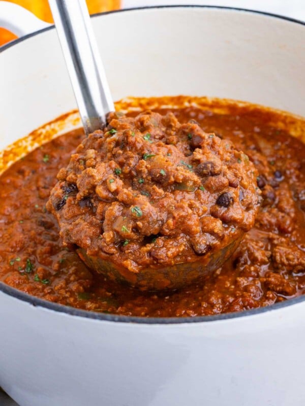 A ladle scoops a thick pumpkin chili out of a pot.