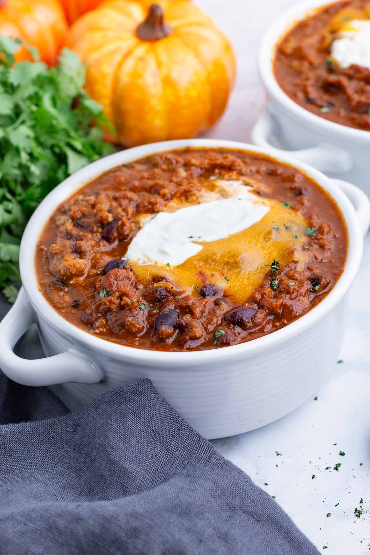 Two bowls of pumpkin chili are topped with cheese and sour cream.