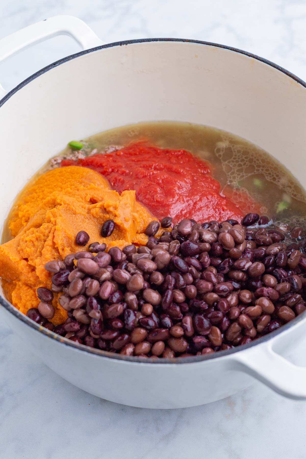 Beans, pumpkin, and tomato are added to the pot.