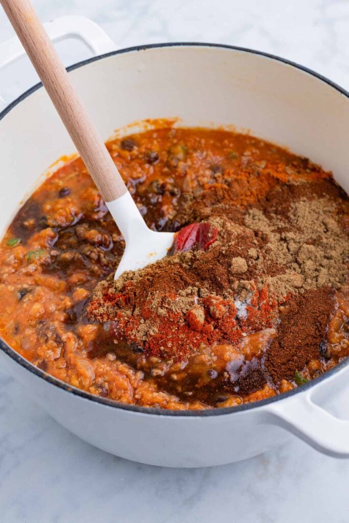 Seasonings are added to the chili ingredients.