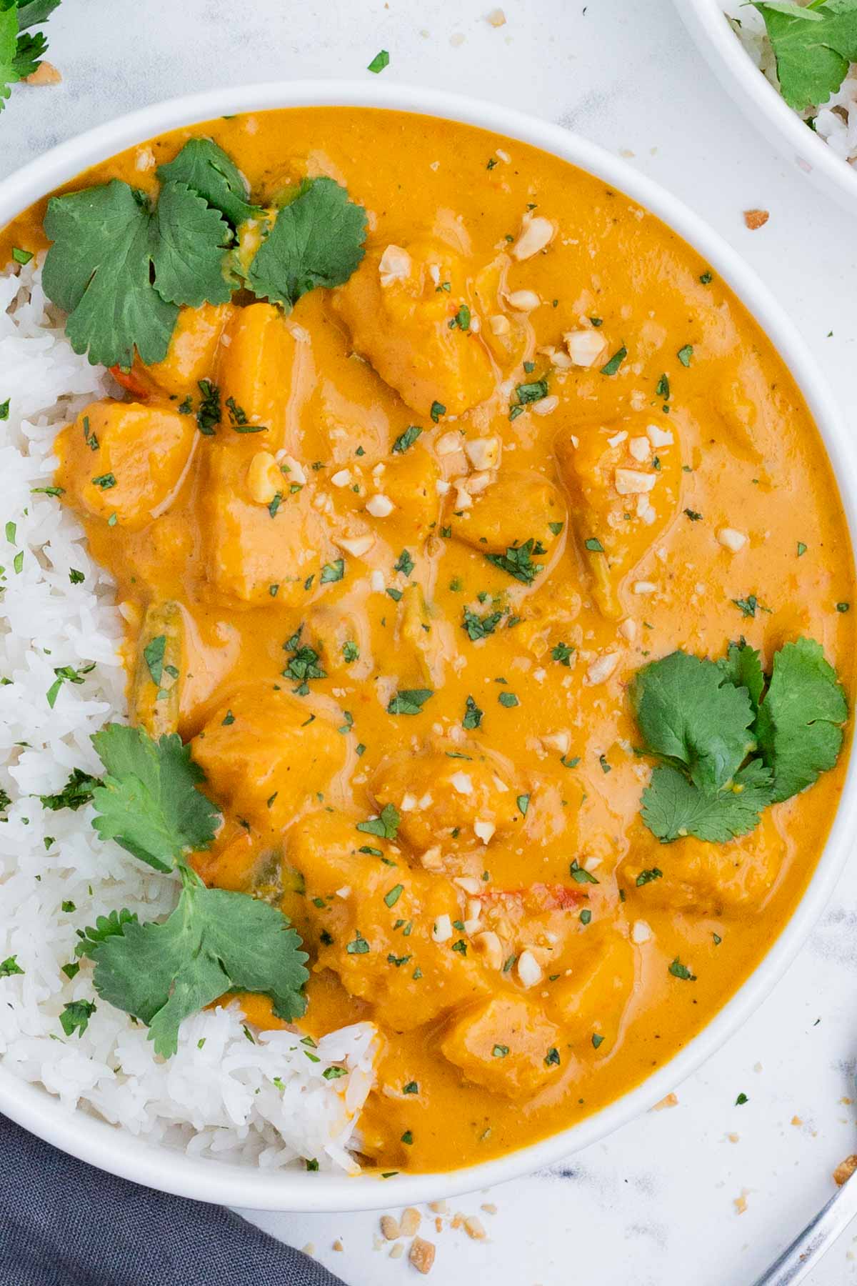 Pumpkin curry is served over rice in a white bowl.
