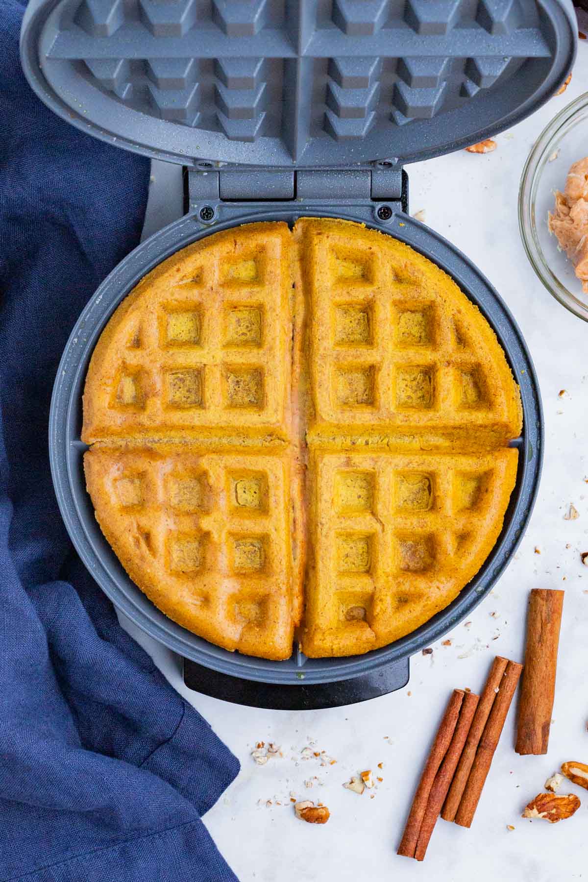 Pumpkin waffles are cooked on a waffle iron.
