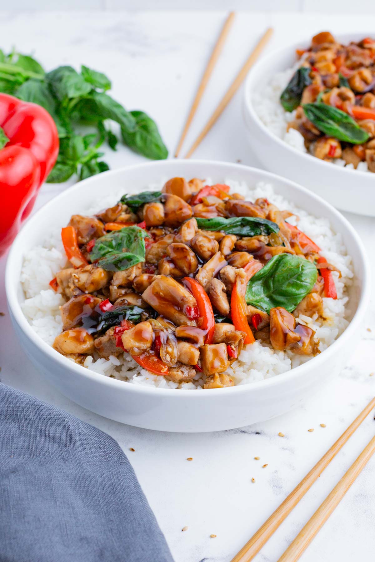 Two bowls of rice are topped with Thai basil chicken.