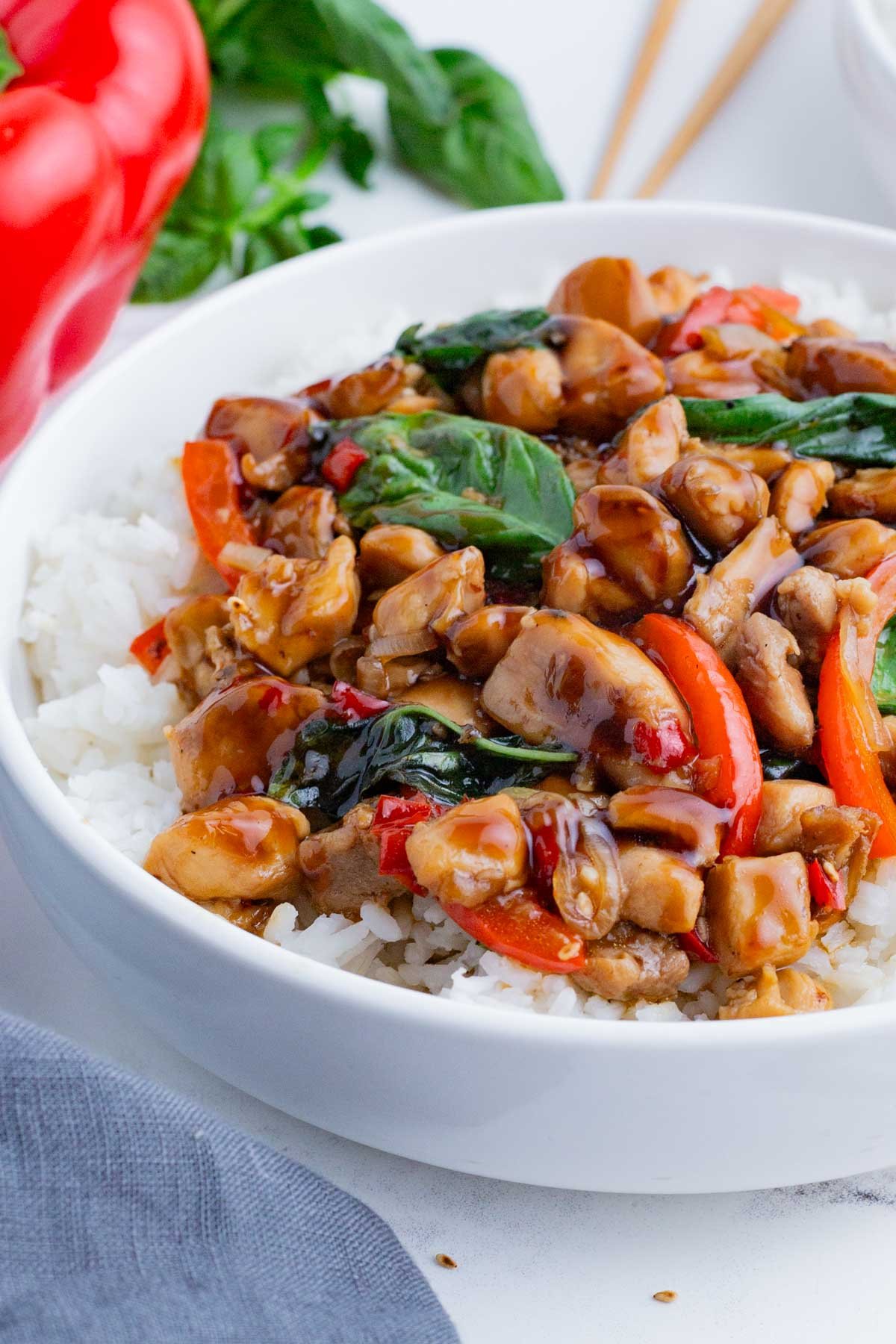 A white bowl is full of Jasmine rice and savory Thai basil chicken.
