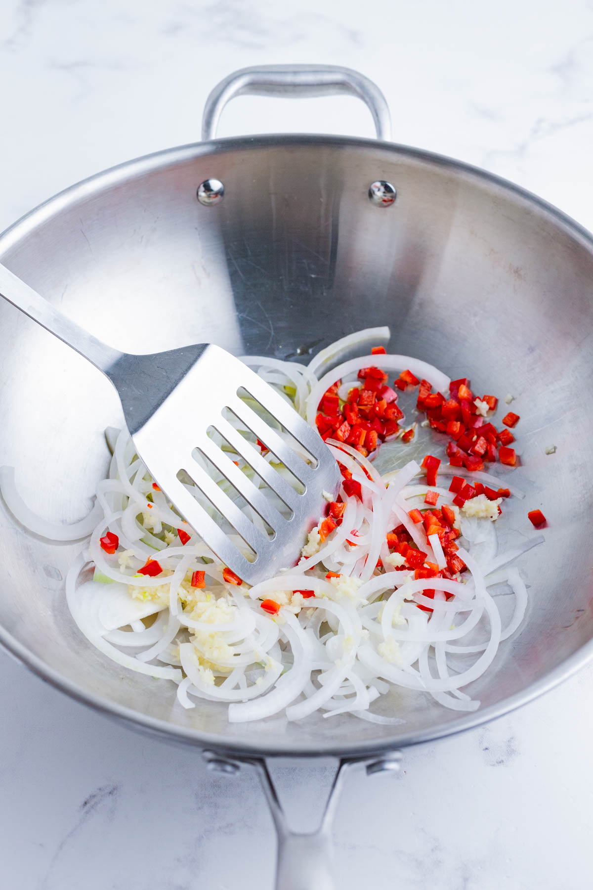 Thai chilies and onion are cooked in a wok.