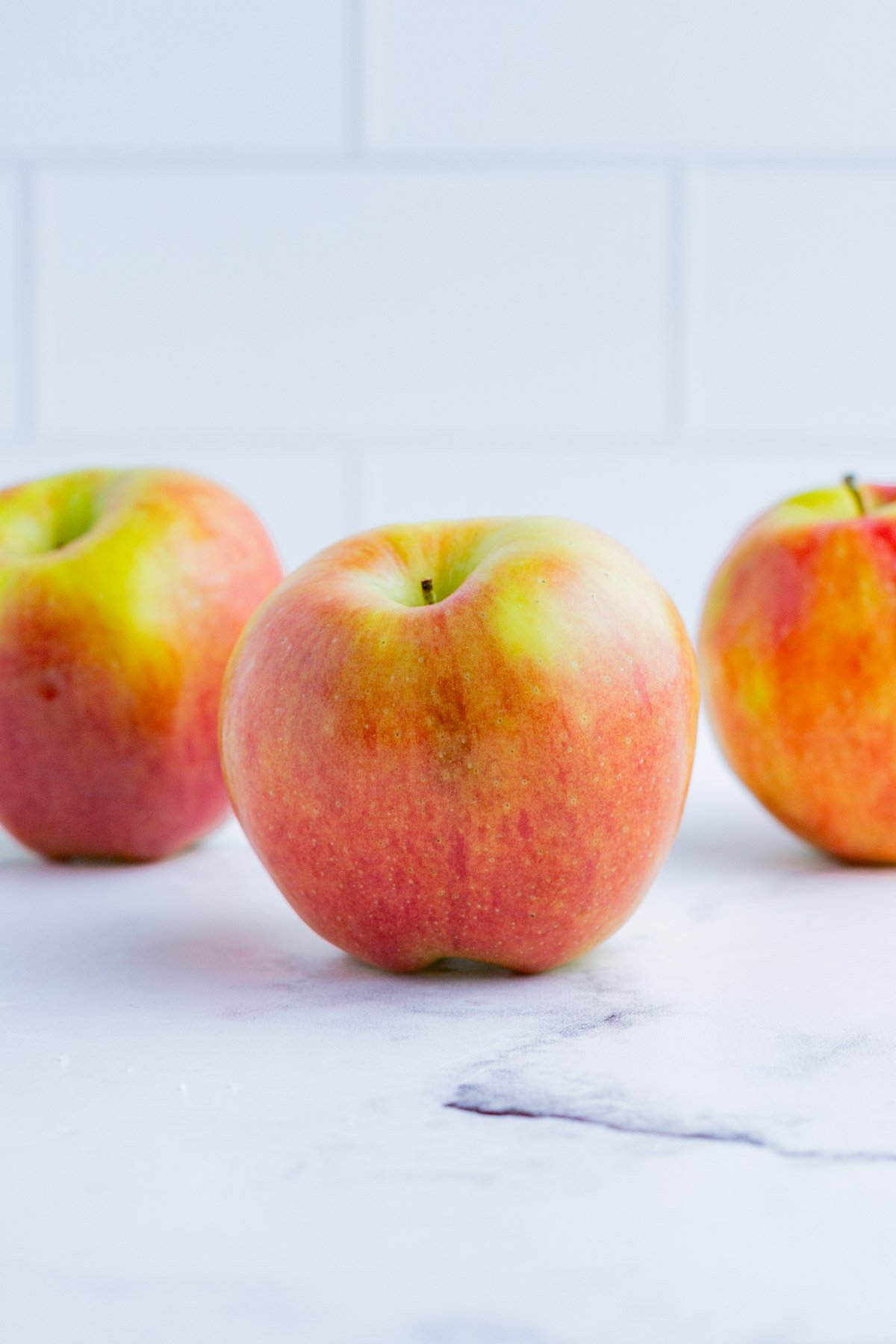 3 Gala apples on the counter top.