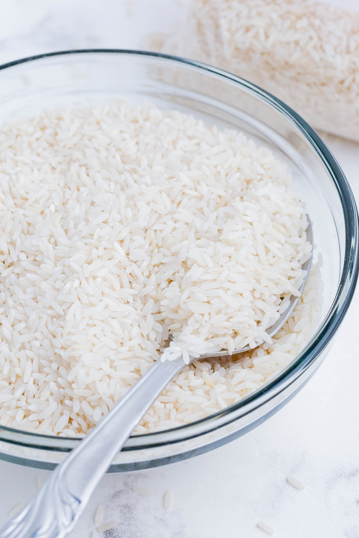 Dry white rice in a clear bowl with a silver spoon.