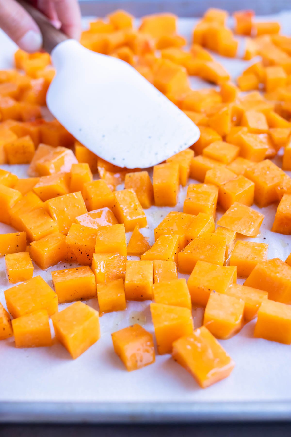 Butternut squash is roasted in the oven on a baking sheet.