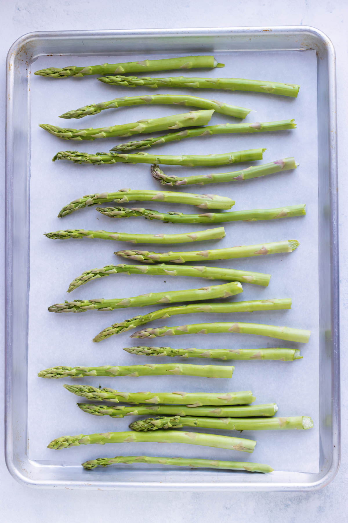 Asparagus spears roast in a single layer on a baking sheet.