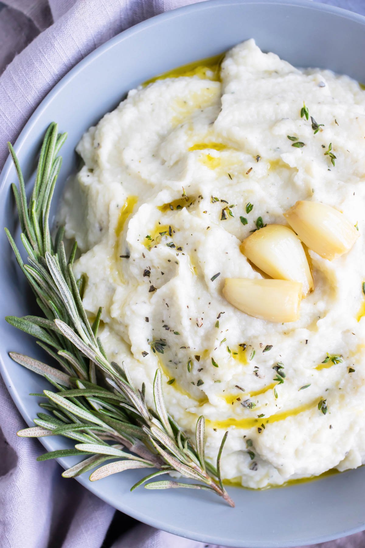 Creamy, healthy, low-carb, and keto cauliflower mash that is being served in a grey bowl for a Thanksgiving side dish.