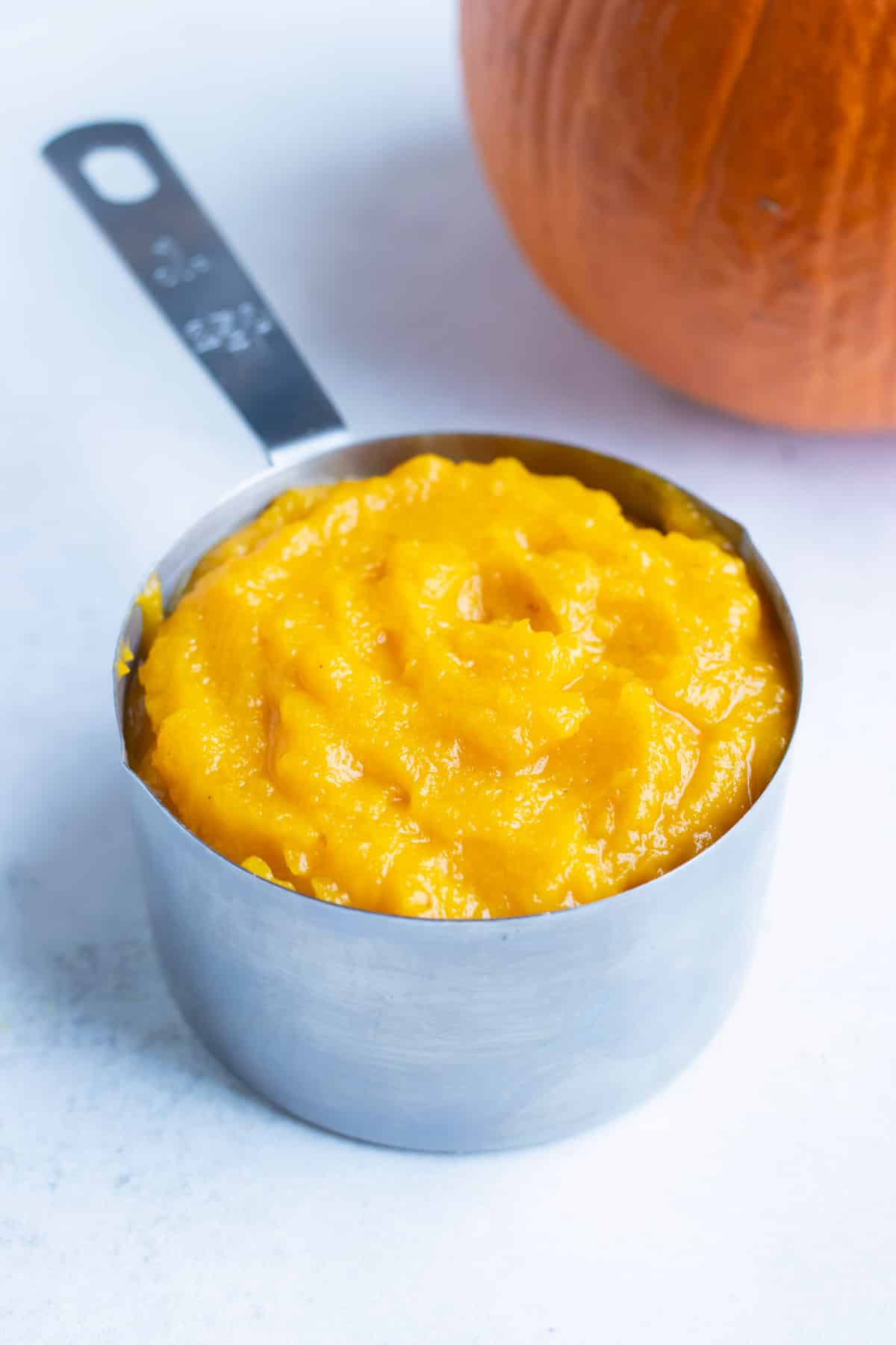 Fresh pumpkin puree is in a measuring cup before being used in pumpkin pie.