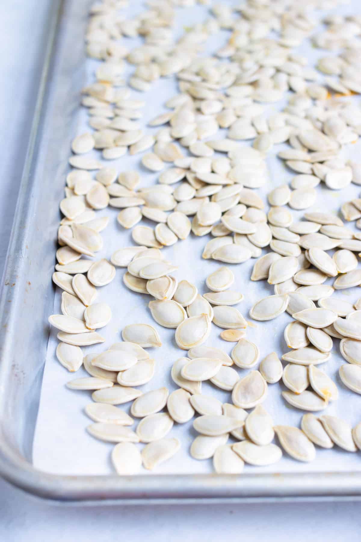 Pumpkin seeds are placed on a baking sheet before being toasted.