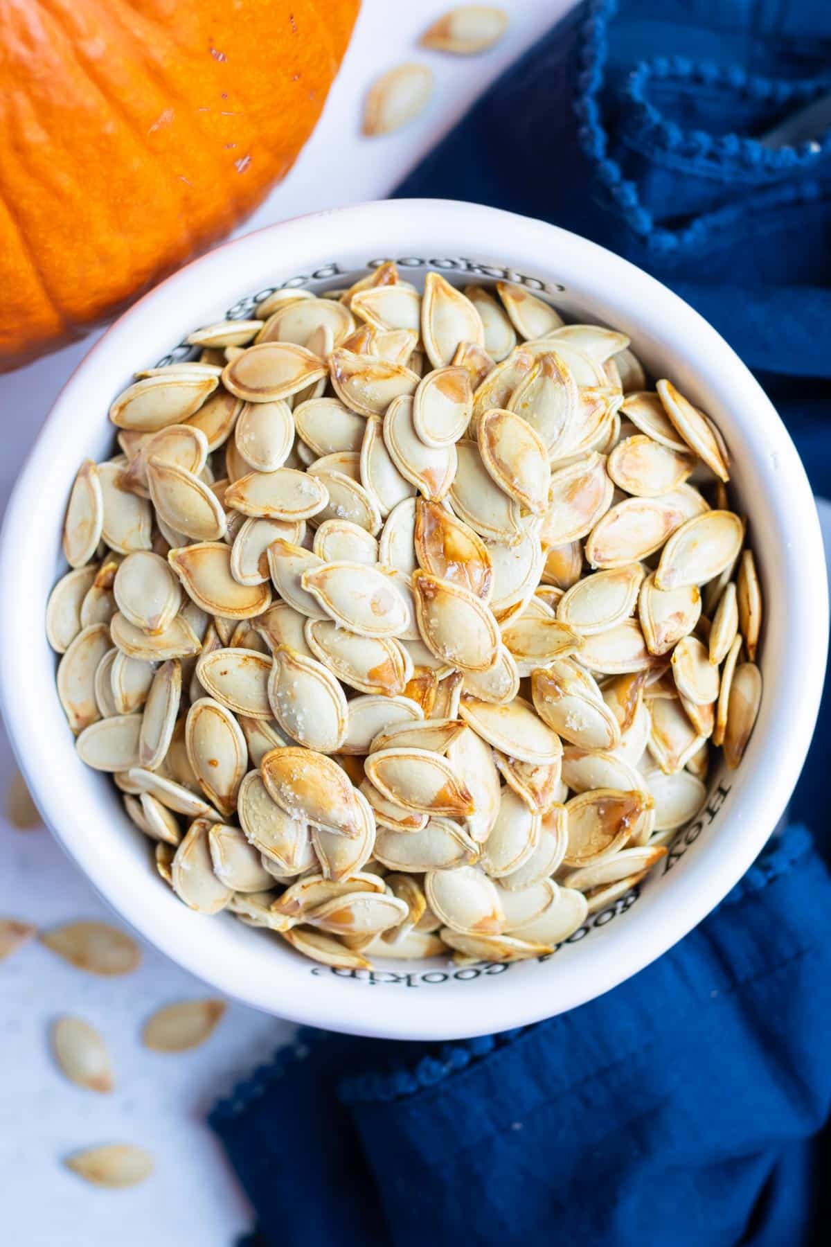 Roasted pumpkin seeds are placed in a bowl before being used in recipes.