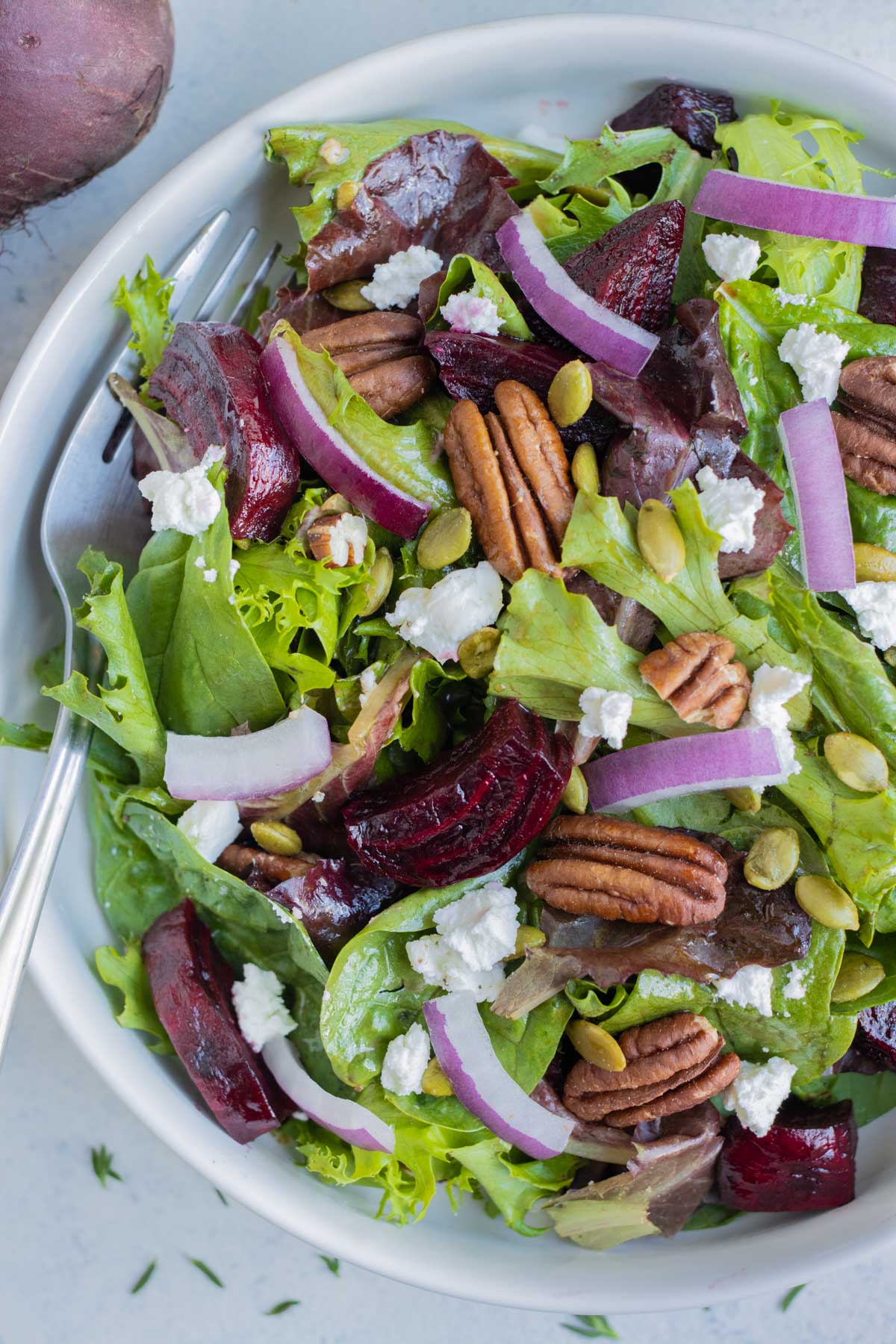 Roasted Beet Salad RECIPE in a white serving bowl and a metal spoon.