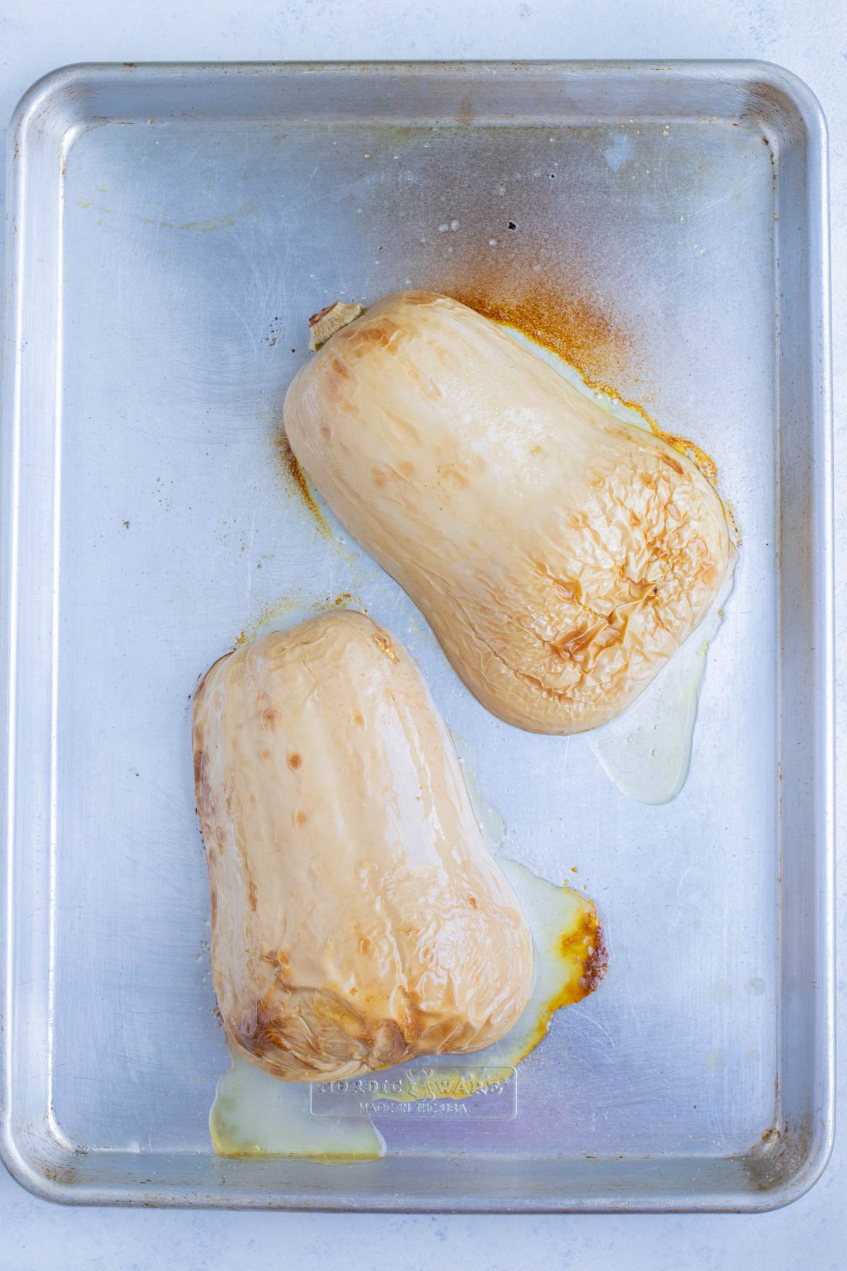 Butternut squash halves are roasted in an oven.