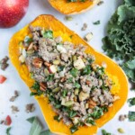 A sausage, kale, and apple mixture are used to fill a roasted butternut squash.