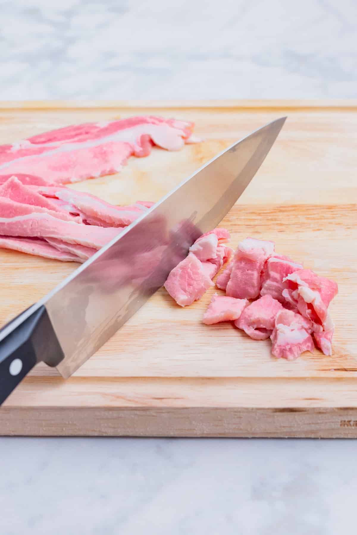 Bacon is sliced by a sharp knife.