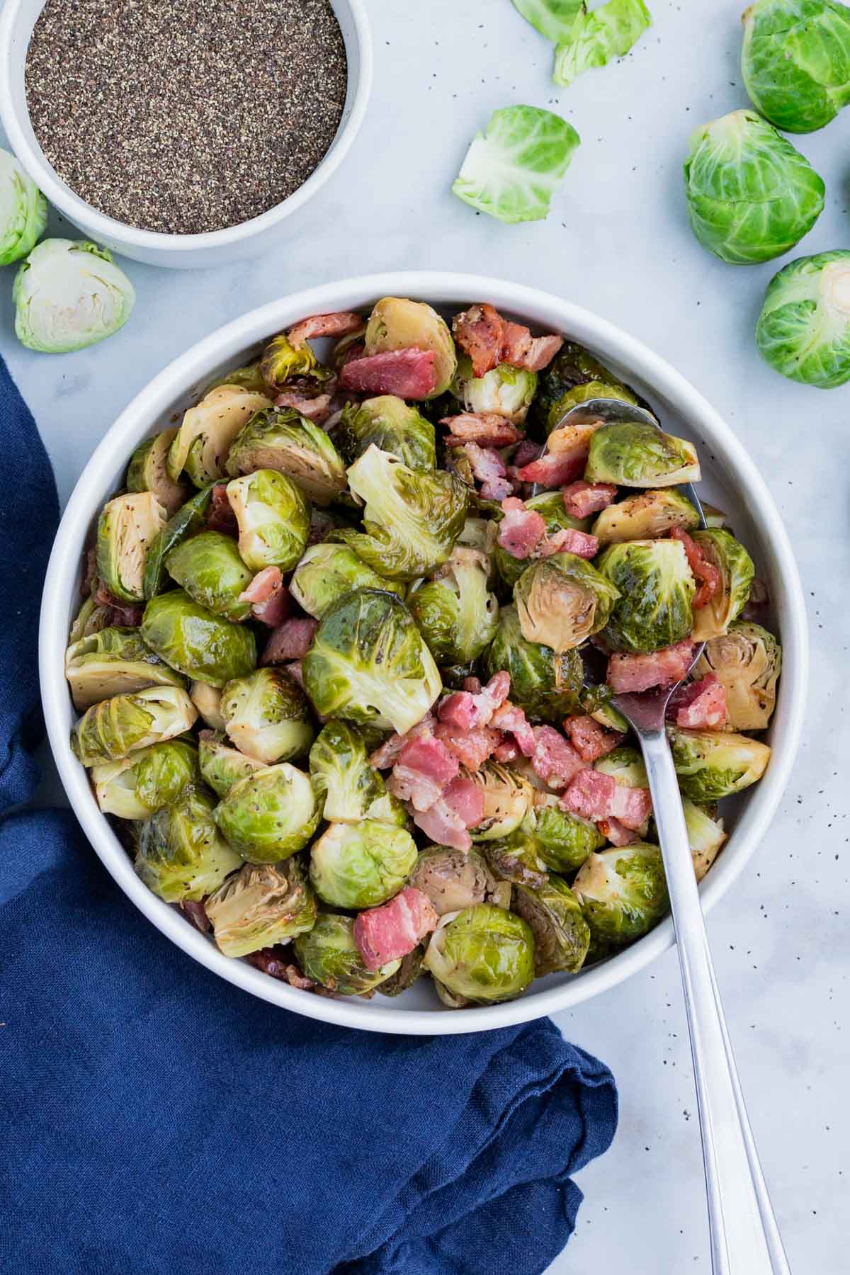 An overhead shot of Brussels sprouts baked with bacon in the oven and served in a white bowl.