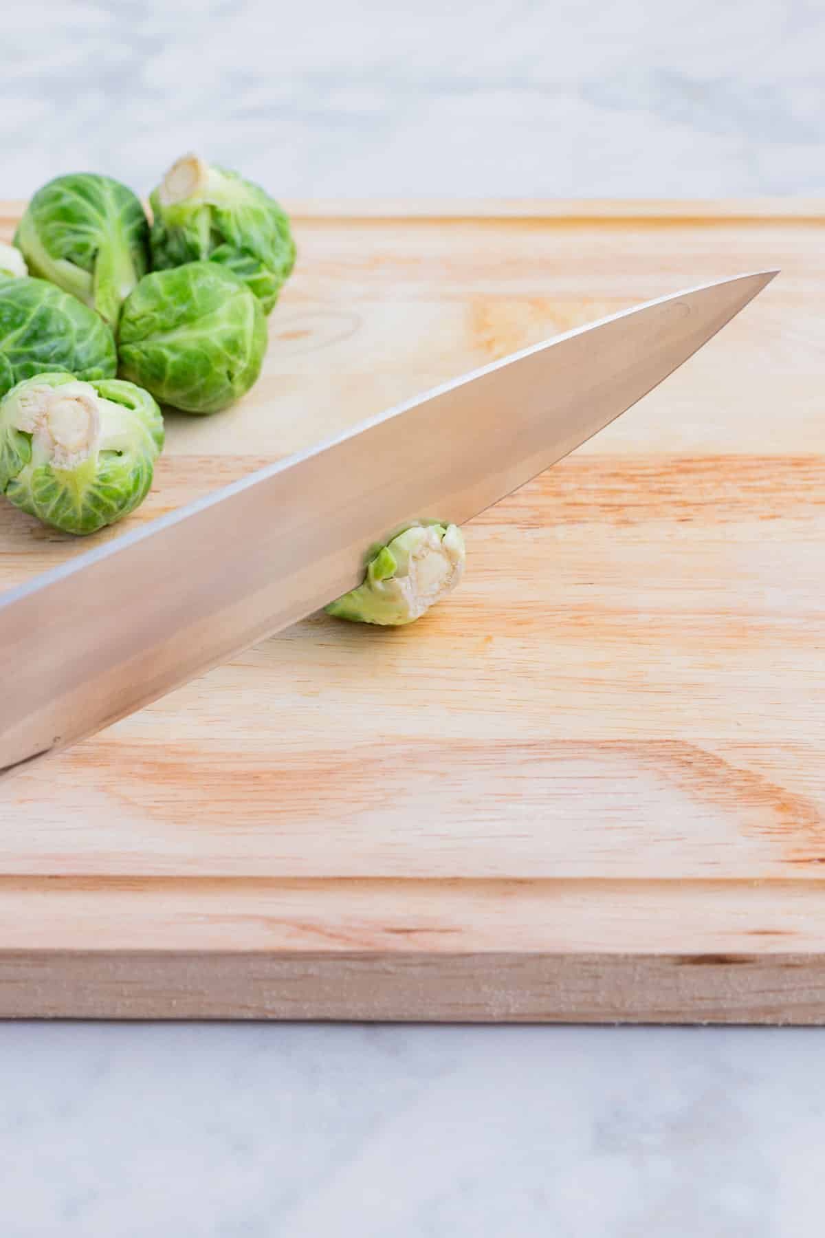A knife removes the end of the Brussels sprouts.