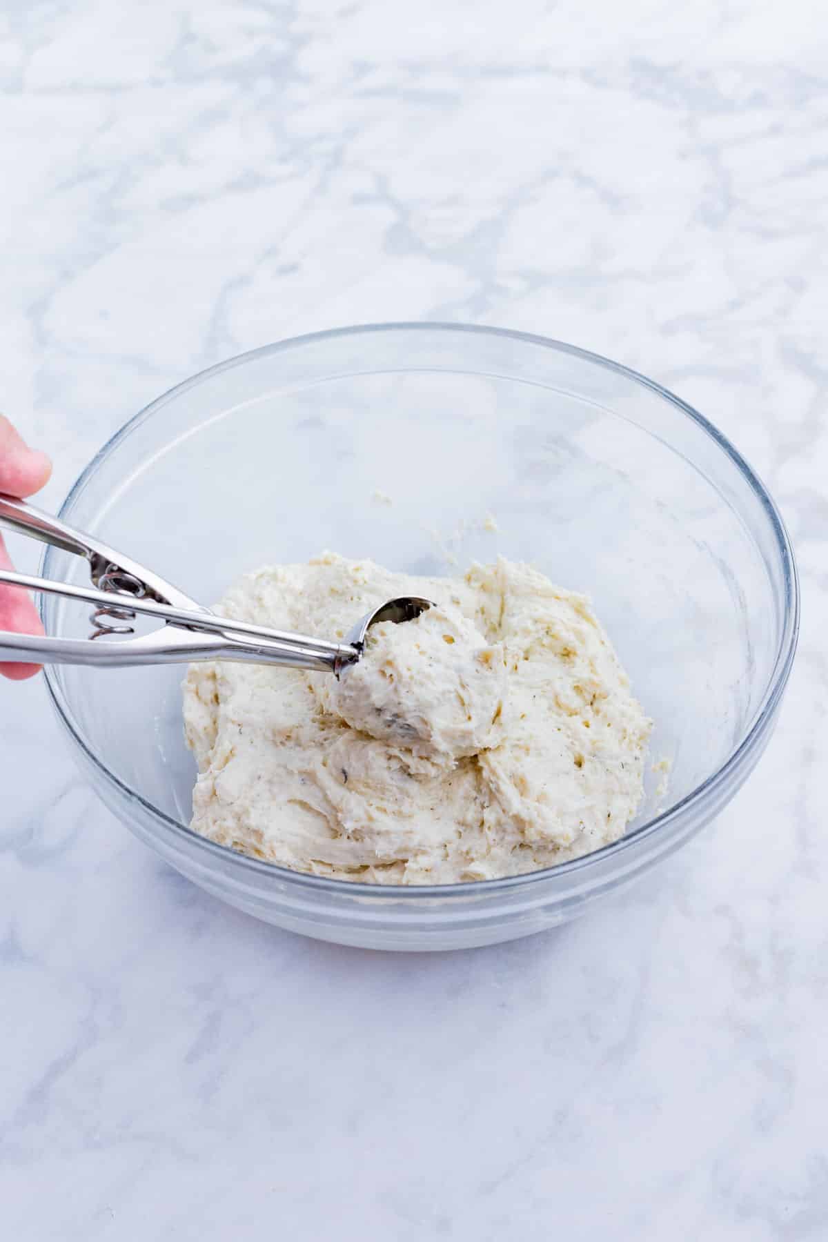 A cookie scoop is used to measure out individual dumplings.