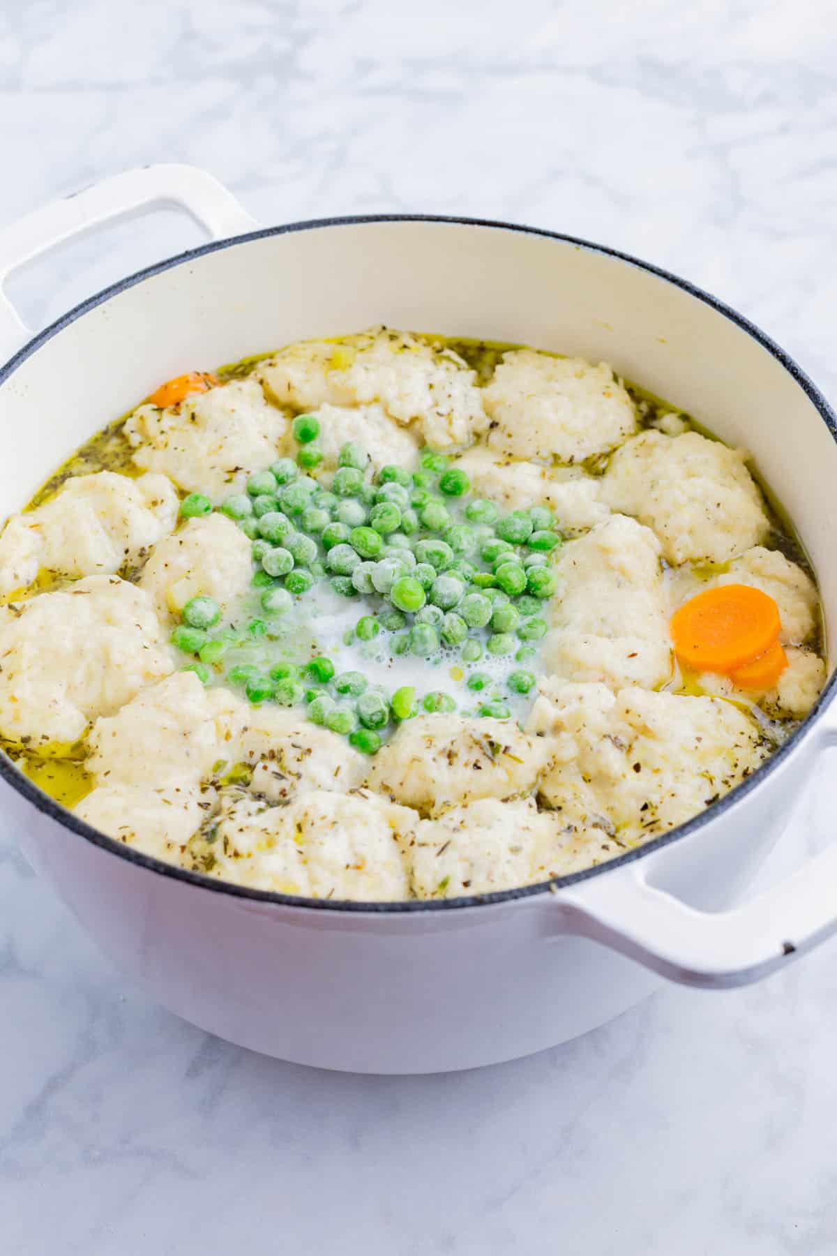Dumplings, peas, and milk are added to the soup base to cook.