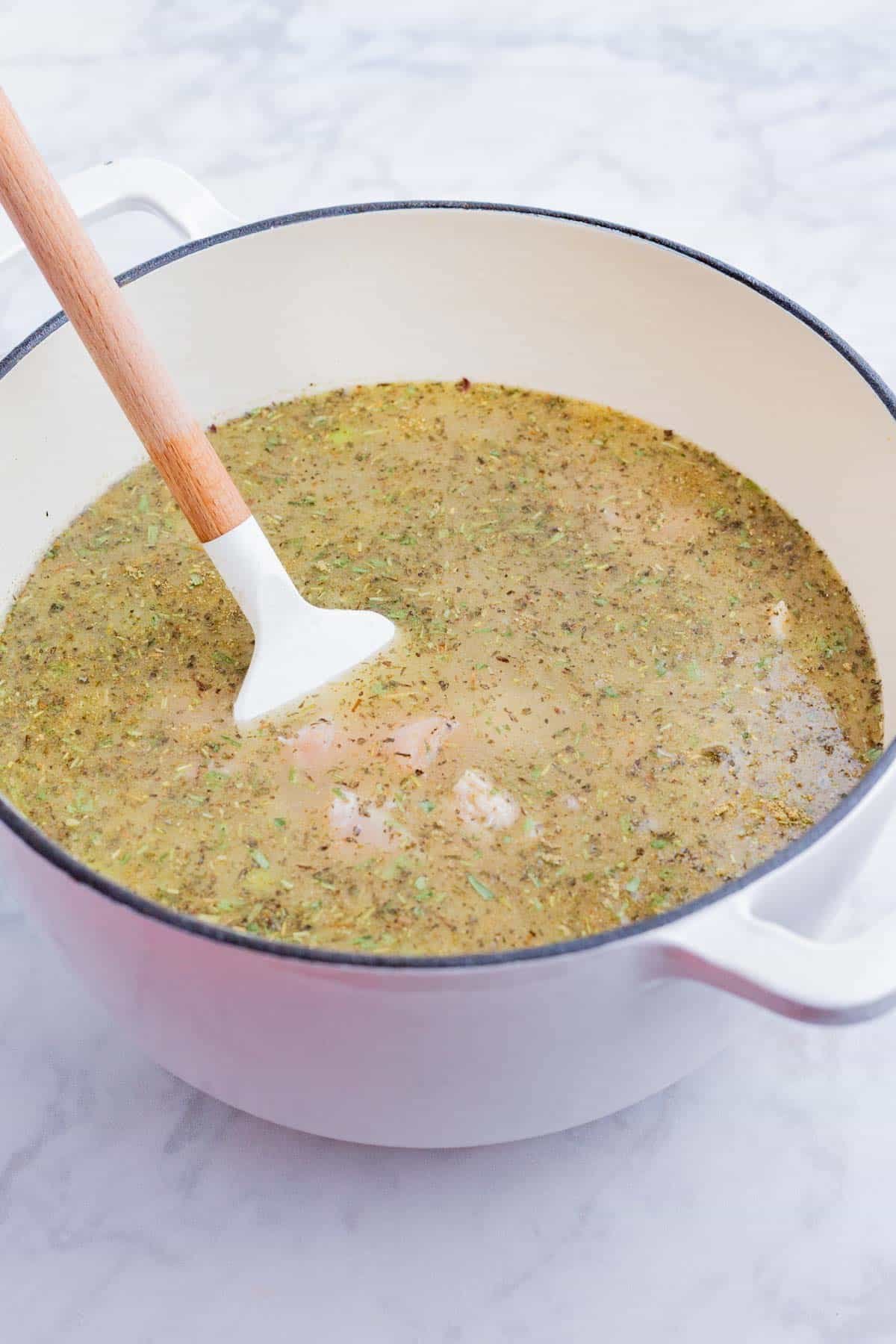 Herbs are stirred into the soup base.