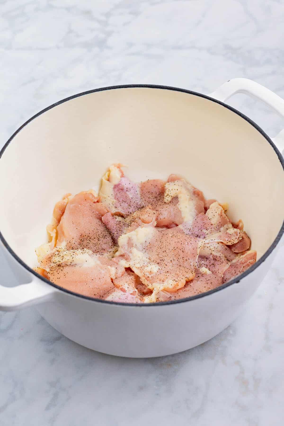 Chicken thighs are cooked in a Dutch oven.