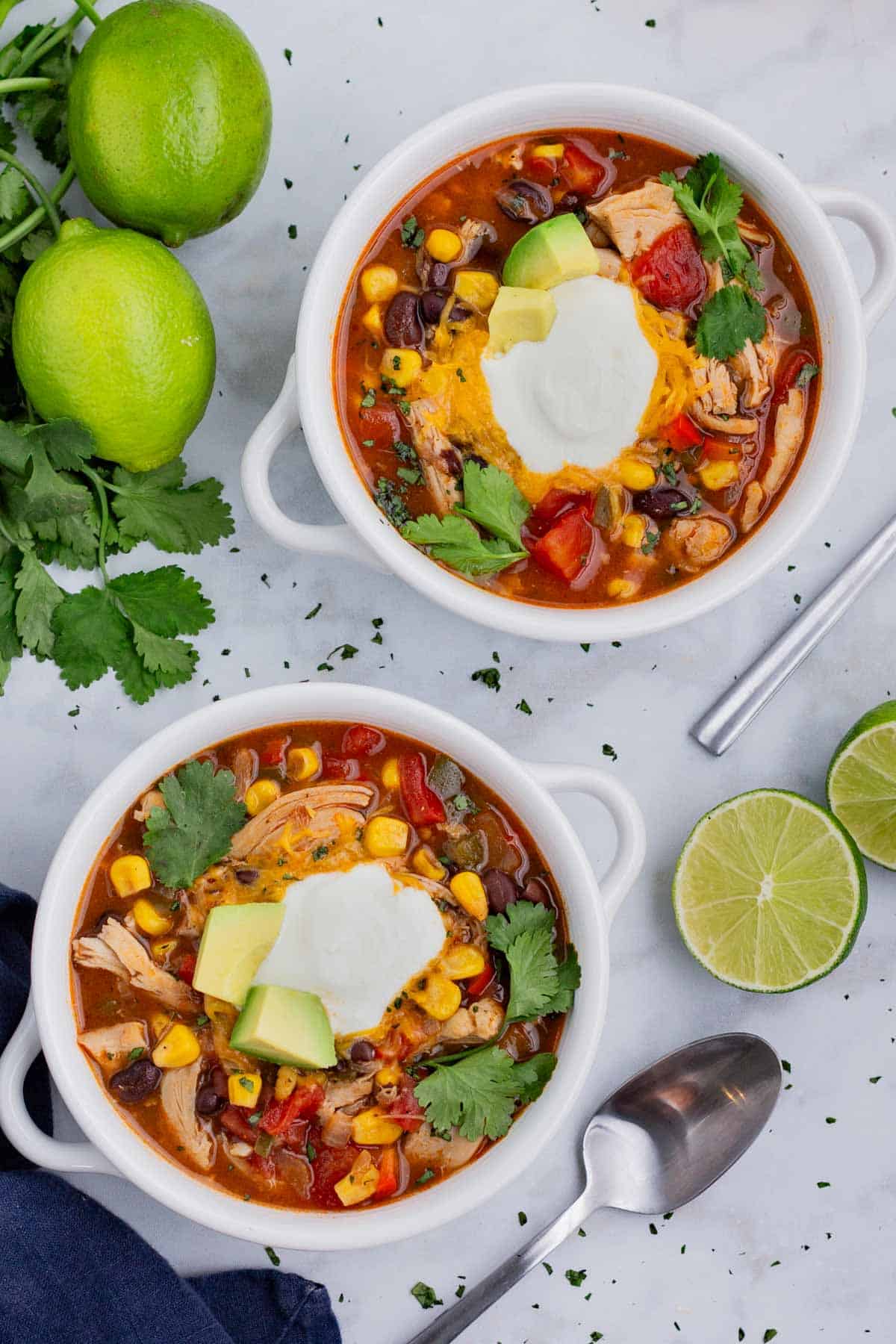 Two soup bowls are filled with chicken enchilada soup before serving on a busy weeknight.