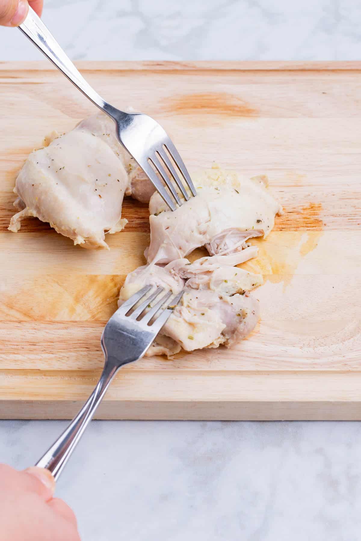 Cooked chicken is shredded before being added back to the dish.