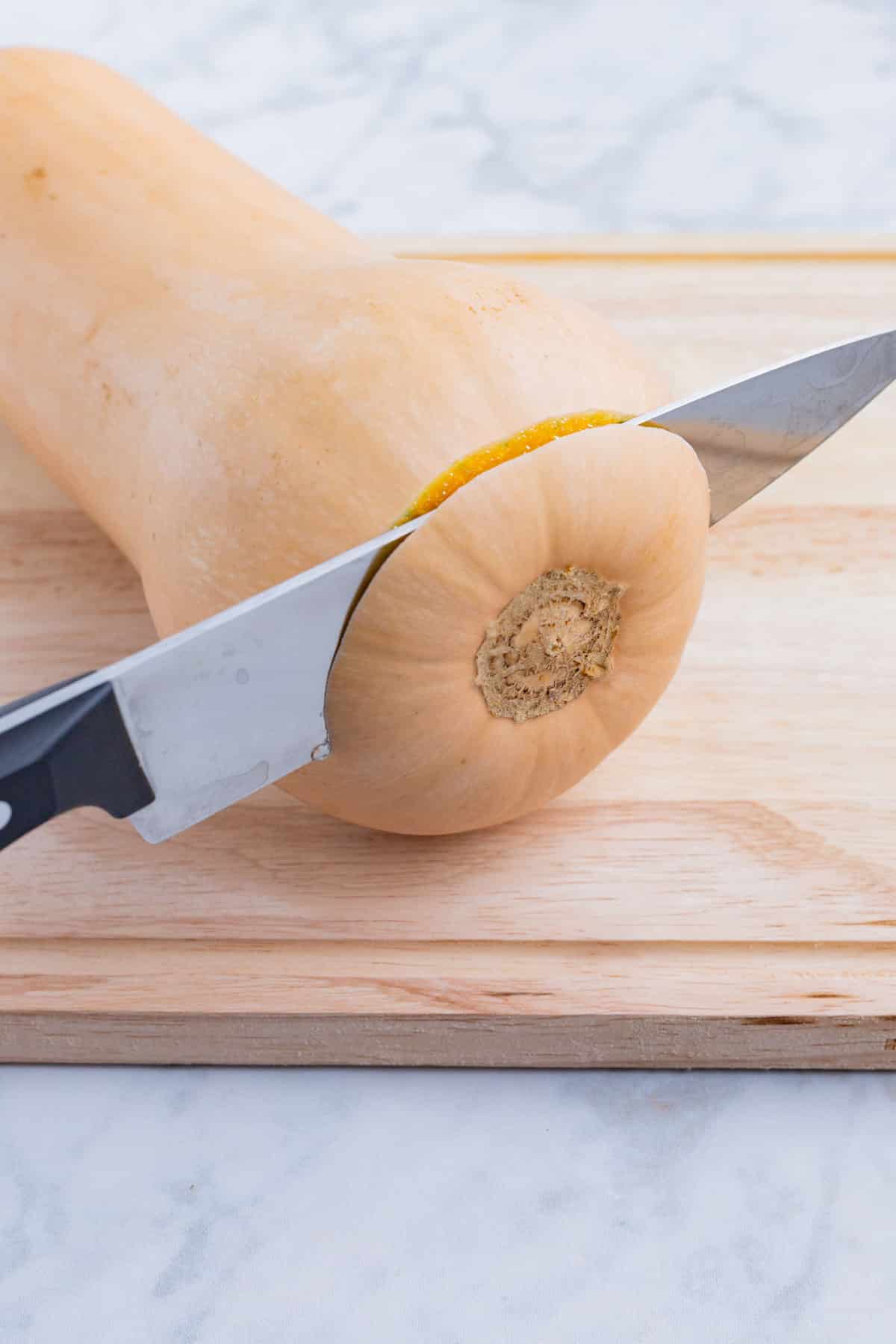 The end is sliced off of a butternut squash.