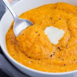 A spoon is used to serve mashed butternut squash for a healthy side dish.