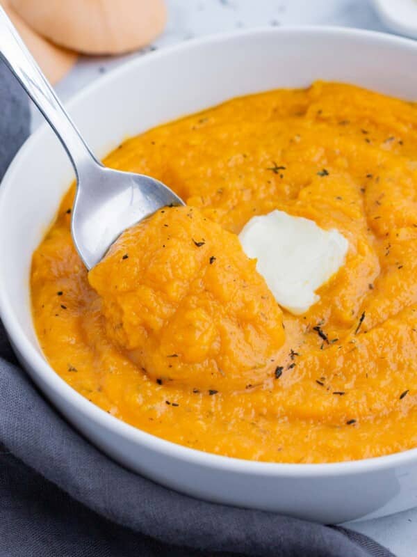 A spoon is used to serve mashed butternut squash for a healthy side dish.
