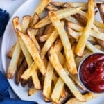 Crispy Air fryer french fries are served on a white plate with a bowl of ketchup.