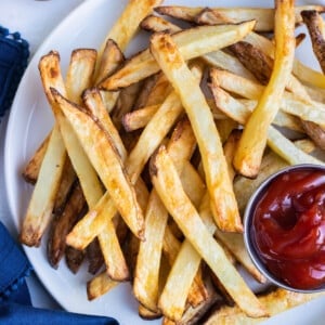 Crispy Air fryer french fries are served on a white plate with a bowl of ketchup.