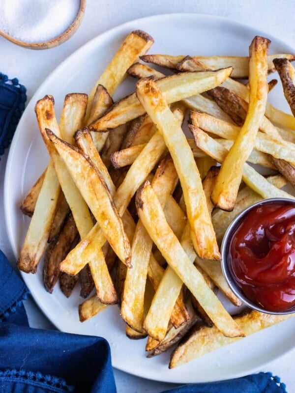 Crispy Air fryer french fries are served on a white plate with a bowl of ketchup.