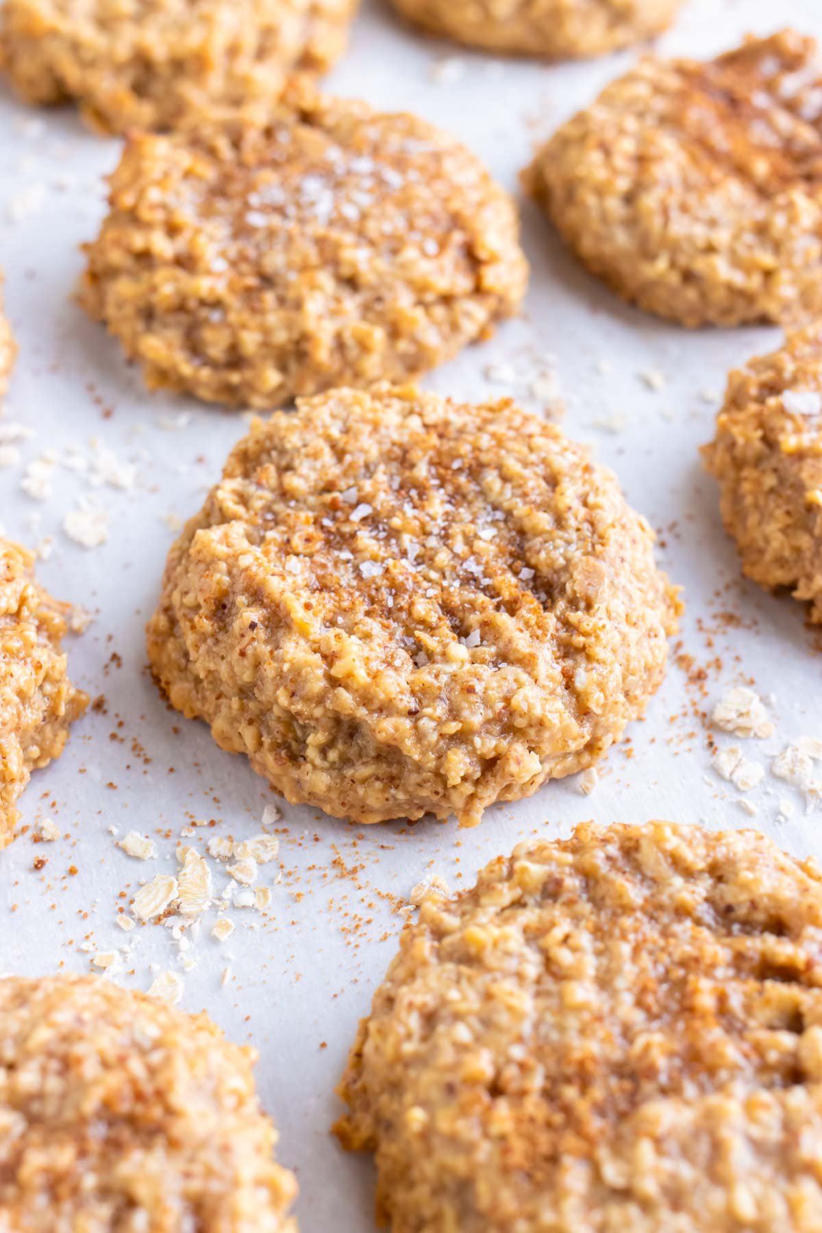 Almond butter oatmeal cookies are cooling on a parchment paper lined baking sheet.