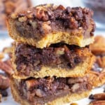 A stack of chocolate pecan pie bars with a bite taken out.