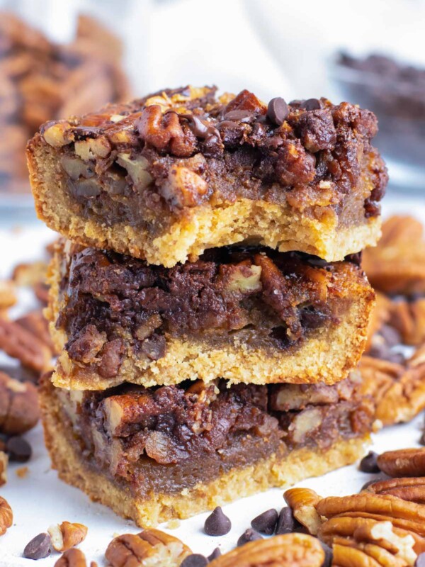 A stack of chocolate pecan pie bars with a bite taken out.