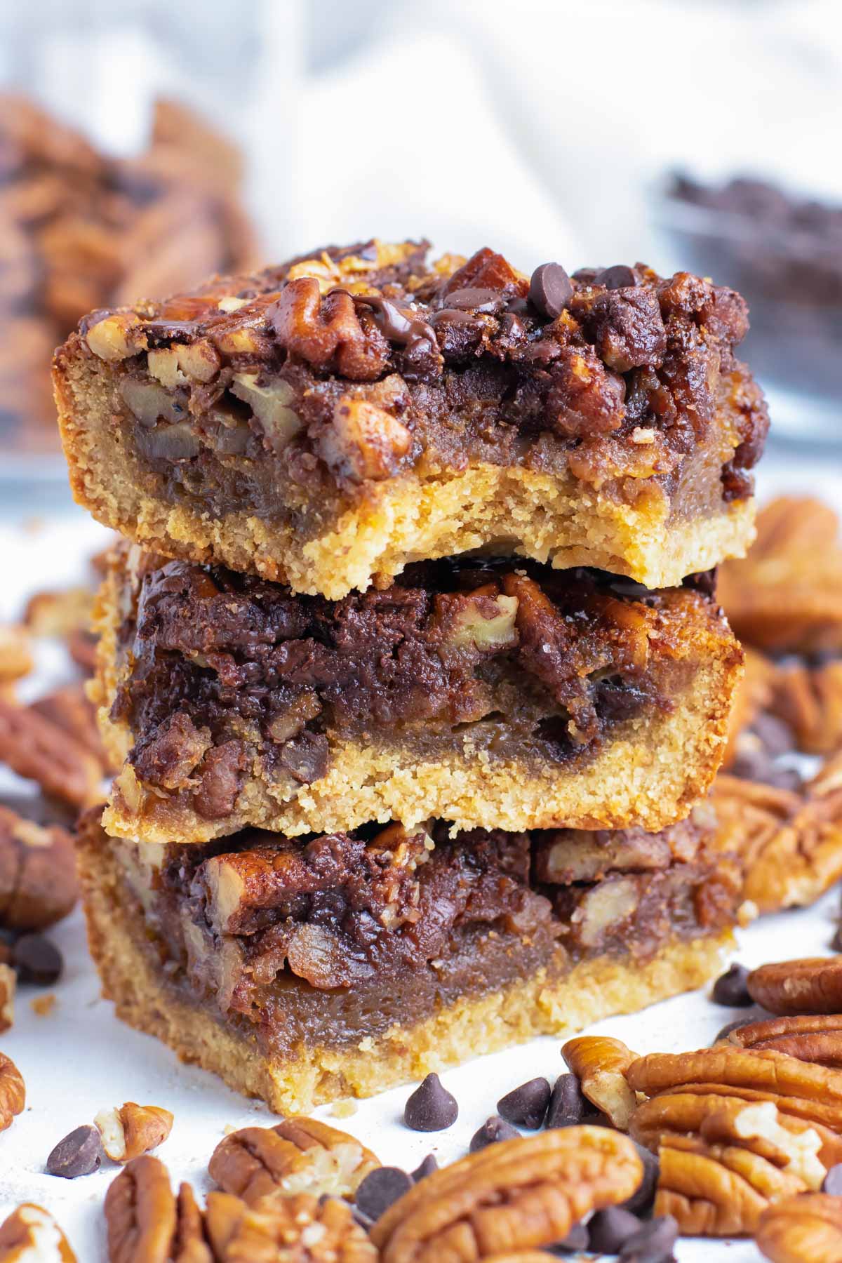 A stack of chocolate pecan pie bars with a bite taken out.