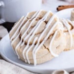 Two cinnamon Roll cookies are served on a white plate with coffee.
