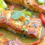 A close-up of a salmon fillet in a coconut milk green curry sauce made with lime juice and curry powder.